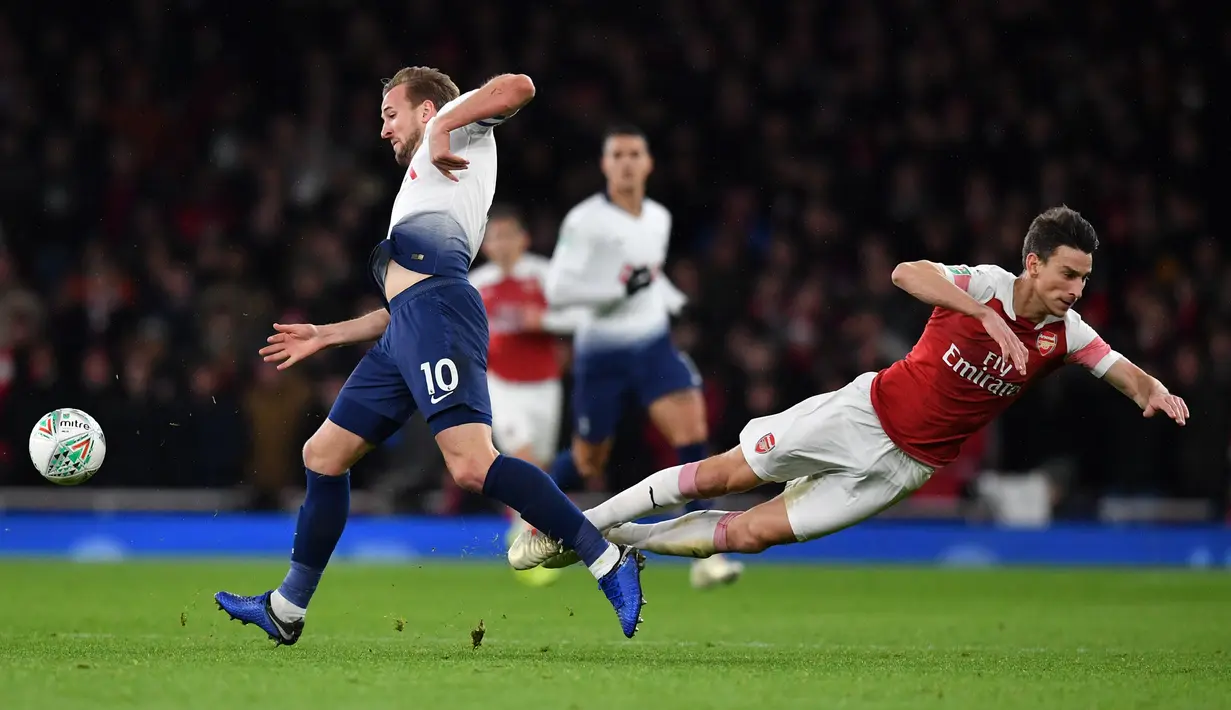 Striker Tottenham Hotspur, Harry Kane merebut bola dari bek Arsenal, Laurent Koscielny pada perempat final Piala Liga Inggris di Stadion Emirates, Kamis (20/12). Tottenham melaju ke babak semifinal seusai menaklukkan Arsenal 2-0. (Ben STANSALL / AFP)