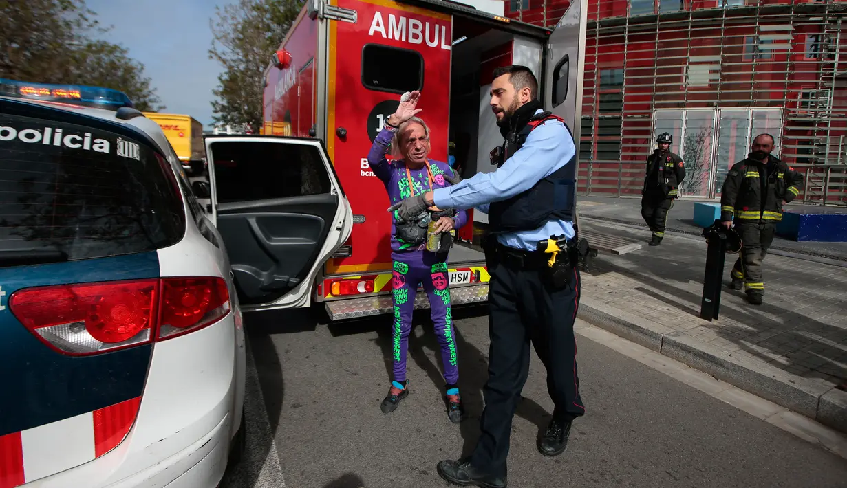 Pendaki pencakar langit, Alain Robert, yang juga dikenal sebagai 'Spiderman Prancis' melambaikan tangan saat ditahan kepolisian usai memanjat Menara Agbar setinggi 144 meter di Barcelona, Rabu (4/3/2020). Alain Robert telah menaklukkan lebih dari 100 bangunan di seluruh dunia. (AP/Joan Mateu)