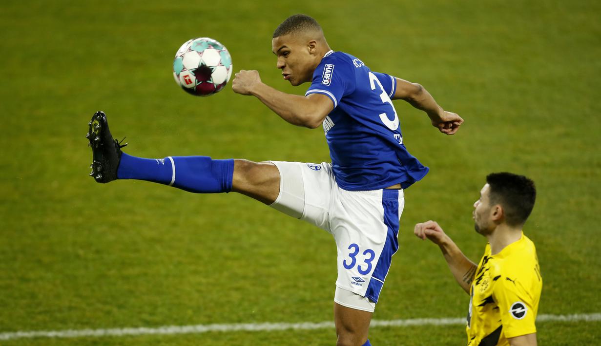Gelandang Schalke, Malick Thiaw (kiri) membuang bola dari ancaman bek Borussia Dortmund, Raphael Guerreiro dalam laga lanjutan Liga Jerman 2020/21 pekan ke-22 di Veltins Arena, Sabtu (20/2/2021). Schalke kalah 0-4 dari Borussia Dortmund. (AP/Leon Kuegeler/Pool)