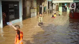 Anak-anak bermain di tengah banjir yang merendam kawasan Rawajati, Jakarta Selatan, Sabtu (8/2/2020). Hujan yang terjadi semalaman menyebabkan Sungai Ciliwung kembali meluap hingga membuat rumah warga di kawasan tersebut terendam air setinggi 50 cm hingga 1 m. (Liputan6.com/Immanuel Antonius)