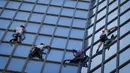 Pendaki Alain Robert (kedua kanan) atau Spiderman Prancis bersama Marcin Banot, Alexis Landot, dan Leo Urban memanjat Menara Total di La Defense, Paris, Prancis, 7 September 2021. Alain dengan tangan kosong memanjat menara setinggi 190 meter itu untuk menentang izin kesehatan. (THOMAS SAMSON/AFP)