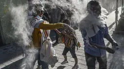 Orang-orang bermain dengan bedak dan busa di jalan selama Karnaval Hitam Putih di Pasto, Kolombia (6/1/2022). Karnaval Hitam Putih, yang telah asal-usulnya dalam campuran ekspresi budaya Andes, Amazon, dan Pasifik. (AFP/Joaqin Sarmiento)