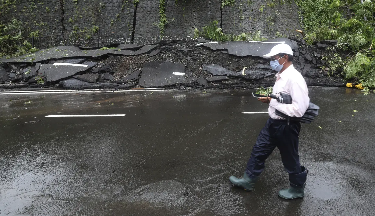 Seorang pria berjalan di dekat jalan yang rusak akibat longsor setelah hujan deras di Mumbai, India, Rabu, (6/8/2020). Musim hujan India berlangsung dari Juni hingga September. (AP Photo / Rafiq Maqbool)