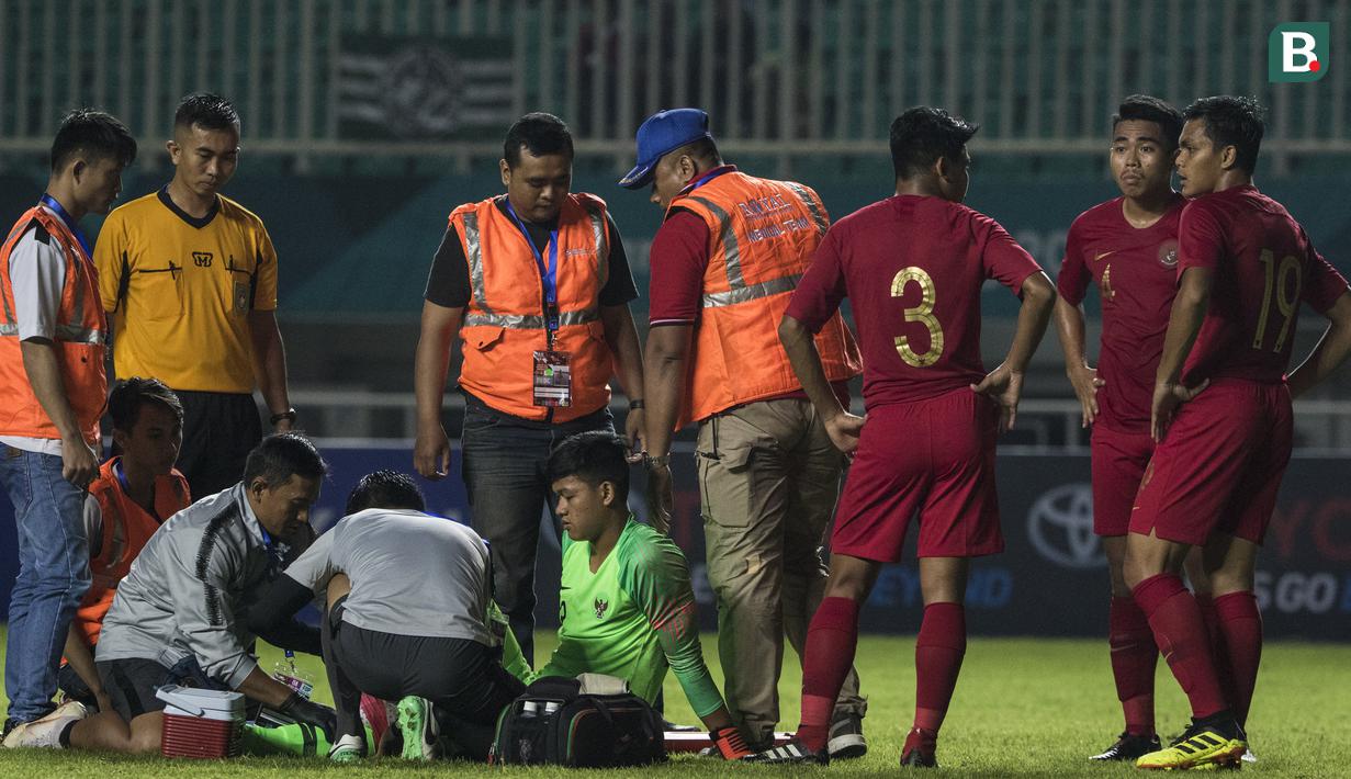 Kiper Timnas Indonesia, Muhammad Riyandi, cedera saat melawan Thailand pada laga PSSI 88th U-19 di Stadion Pakansari, Jawa Barat, Minggu (23/9/2018). Kedua negara bermain imbang 2-2. (Bola.com/Vitalis Yogi Trisna)