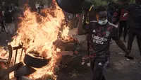 Seorang demonstran berjalan melewati barikade yang dibakar selama protes untuk mendukung pemimpin oposisi utama Ousmane Sonko di Dakar, Senegal, Senin (29/5/2023). (AP Photo/Leo Correa)