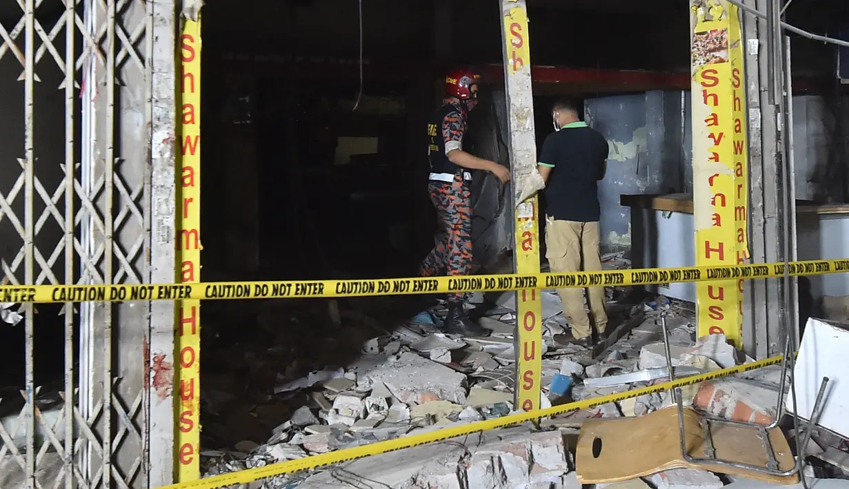 Petugas pemdam kebakaran memeriksa tempat kejadian setelah dugaan ledakan gas di jalanan ramai di Moghbazar, Dhaka, Bangladesh, Minggu (27/6/2021). Tujuh bangunan lain di dekatnya dan tiga bus hancur akibat ledakan. (Munir Uz zaman/AFP)
