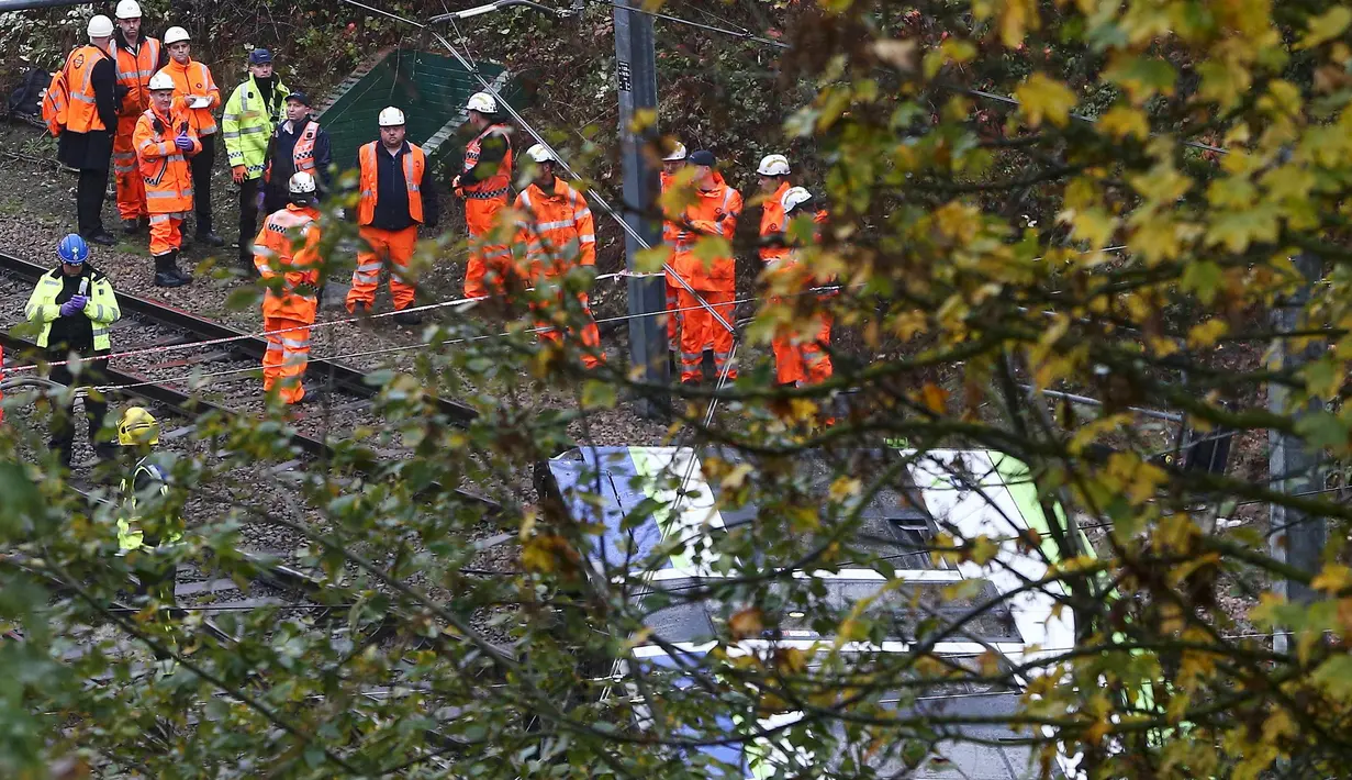 Petugas layanan darurat berkumpul di lokasi terbaliknya sebuah trem di sebuah terowongan di Croydon, London Selatan, Inggris, Rabu (9/11). Masinis trem telah diamankan dan tim penyelidik mulai mencari tahu penyebab kecelakaan. (REUTERS/Neil Hall)