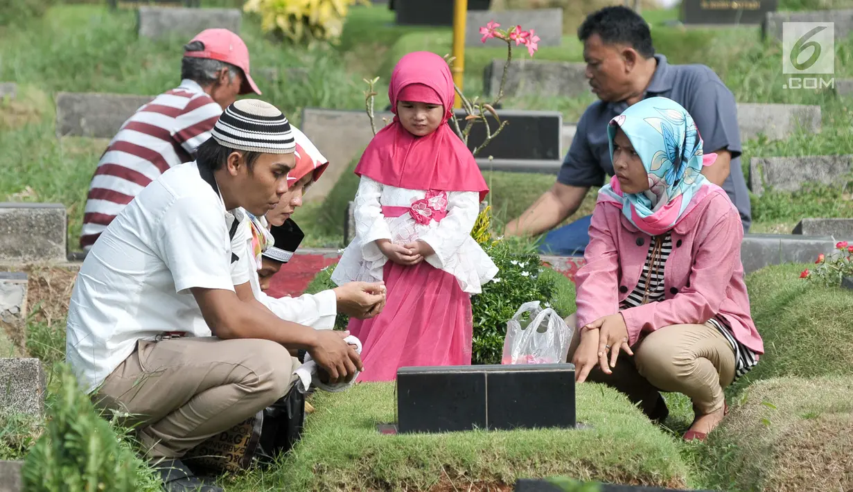 Umat muslim berdoa di makam keluarga saat ziarah kubur di Tempat Pemakaman Umum (TPU) Karet Bivak, Jakarta, Minggu (25/6). Tradisi ziarah yang dilakukan orang muslim setelah melakukan salat Idul Fitri adalah acara tahunan. (Liputan6.com/Yoppy Renato)