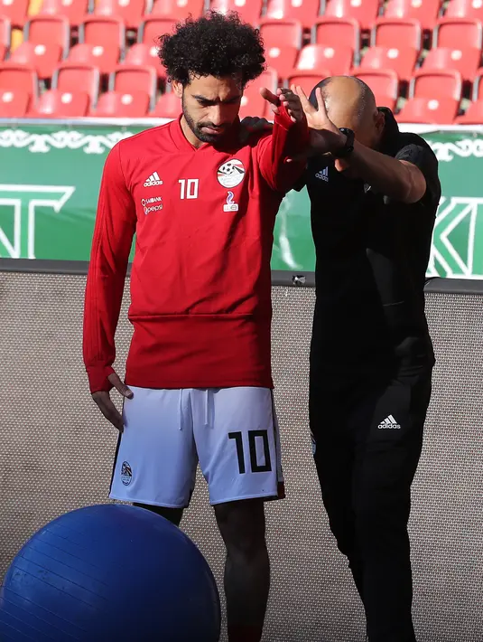 Pemain timnas Mesir Mohamed Salah dibantu tim kesehatan melatih bahunya yang cedera saat pelatihan di stadion Akhmat Arena di Grozny (12/6). Timnas Mesir berada di grup bersama Uruguay, Arab Saudi dan Rusia. (AFP Photo/Karim Jaafar)