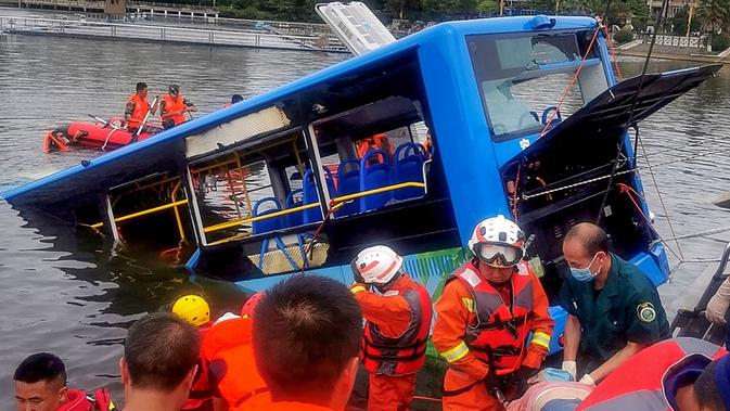 Tim penyelamat berusaha mengevakuasi sebuah bus yang jatuh ke danau di Anshun, provinsi Guizhou, China, Selasa (7/7/2020). Sedikitnya 21 orang tewas usai bus yang  membawa siswa untuk mengikuti ujian masuk perguruan tinggi atau gaokao itu menabrak pagar pembatas lalu tercebur ke danau. (STR/AFP)