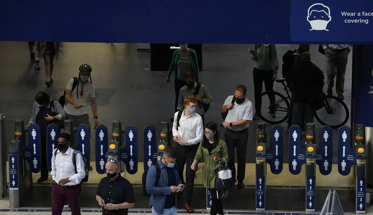 Orang-orang memakai masker saat melewati penghalang tiket setelah turun dari kereta di stasiun Waterloo di London, Rabu (13/7/2021). Wali Kota Sadiq Khan menekankan transportasi publik di London akan terus memberlakukan kewajiban memakai masker setelah Senin (19/7) mendatang. (AP Photo/Matt Dunham)