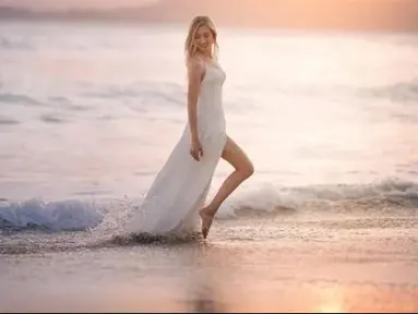Pinggir pantai, dan matahari menjadi pasangan yang cocok untuk Varsha Strauss Adhikumoro berpose mengenakan gaun putih panjang di pinggir pantai. (Foto: Instagram/varshaadhikumoro)