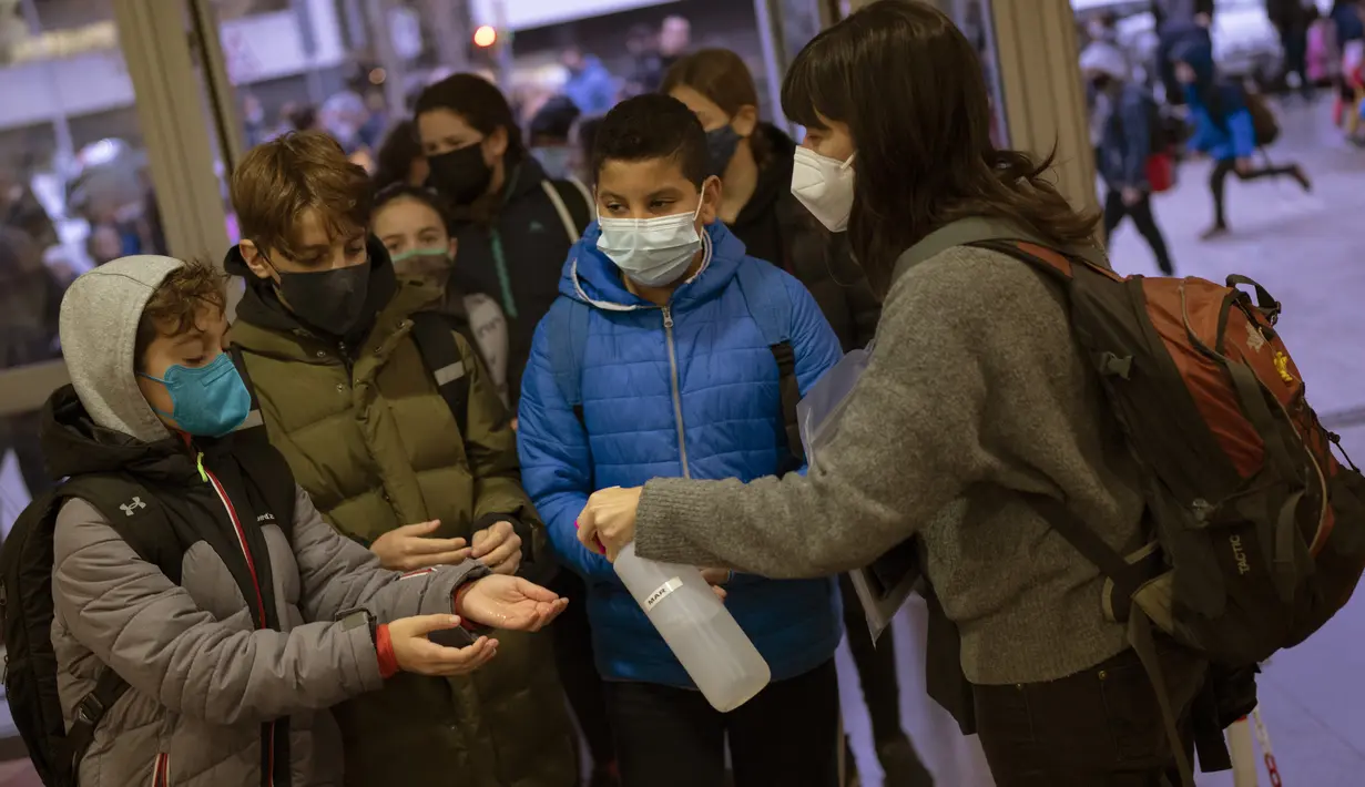 Siswa sekolah dasar mendisinfeksi tangan mereka saat melanjutkan aktivitas setelah liburan Natal di Barcelona, Spanyol, Senin (10/1/2022). Sekitar 8 juta siswa sekolah dasar dan menengah melanjutkan kelas setelah libur panjang Natal dan Tahun Baru. (AP/Emilio Morenatti)