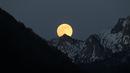 Bulan purnama tampak di belakang pegunungan Alpen yang tertutup salju di Buching, Jerman selatan, (10/5). (Karl-Josef Hildenbrand/dpa/AFP)