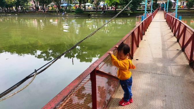 <p>Jembatan yang membelah danau di Kambang Iwak Family (KIF) Park, menjadi salah satu lokasi yang diminati para pengunjung (Liputan6.com / Nefri Inge)</p>