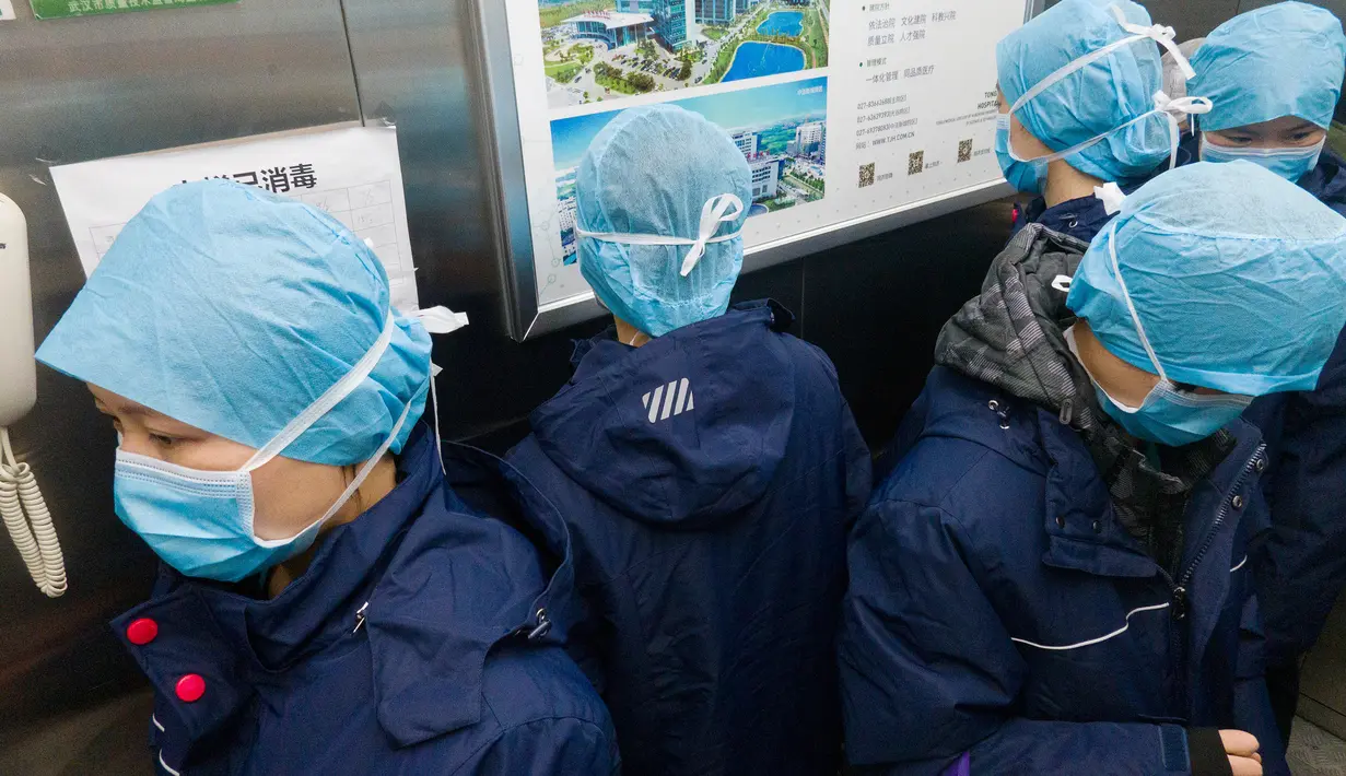 Para petugas medis berdiri menghadap arah yang saling berlawanan demi mencegah risiko infeksi silang virus corona saat menggunakan lift di Rumah Sakit Tongji cabang Guanggu di Wuhan, Provinsi Hubei, China, pada 20 Februari 2020. (Xinhua/Cai Yang)