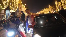 Suporter membawa bendera Prancis bersorak di jalan Champs Elysees usai kemenangan pertandingan semifinal Piala Dunia 2022 melawan Maroko, di Paris, Kamis (15/12/2022). Prancis berhasil mengalahkan Maroko dengan skor 2-0 dan melaju ke babak final menghadapi Argentina. (AP Photo/Thibault Camus)