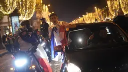 Suporter membawa bendera Prancis bersorak di jalan Champs Elysees usai kemenangan pertandingan semifinal Piala Dunia 2022 melawan Maroko, di Paris, Kamis (15/12/2022). Prancis berhasil mengalahkan Maroko dengan skor 2-0 dan melaju ke babak final menghadapi Argentina. (AP Photo/Thibault Camus)