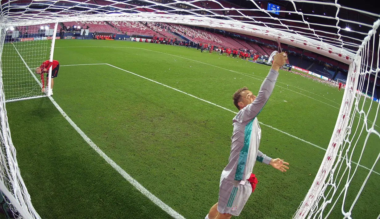 Kiper Bayern Munchen, Manuel Neuer memotong jaring gawang saat merayakan timnya meraih trofi Liga Champions usai mengalahkan PSG pada pertandingan final di stadion Luz di Lisbon (23/8/2020). Munchen menang tipis atas PSG 1-0. (AFP/Lluis Gene)