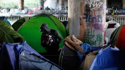 Seorang pria berada di sekitar tenda sementara di samping kanal di Paris, Prancis (30/5). Kamp bawah jembatan di Paris ini sudah sering dibersihkan, namun para pendatang asing kembali menempati tempat tersebut. (AP/Thibault Camus)