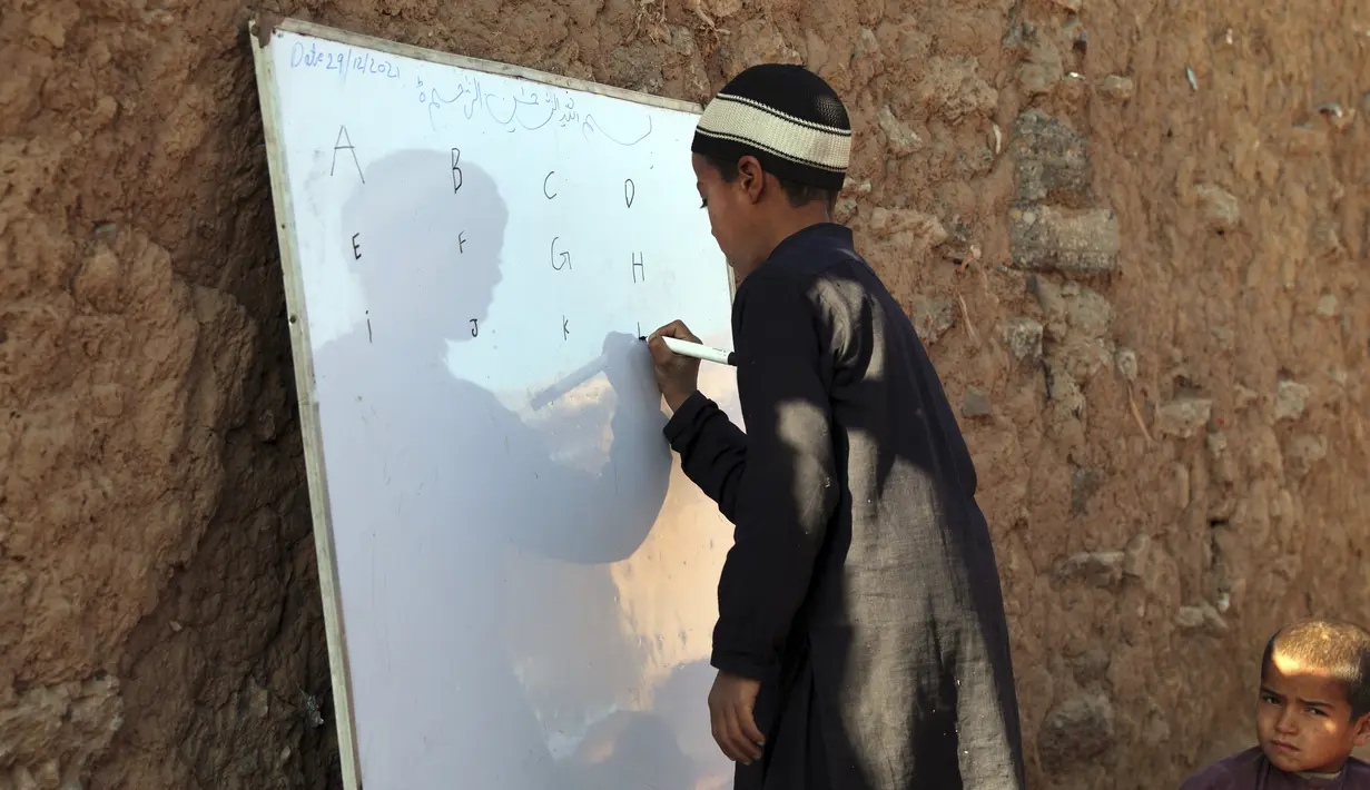 Seorang anak sekolah pengungsi Afghanistan berlatih alfabet Inggris di sebuah sekolah darurat di pinggiran Islamabad, Pakistan, Rabu (29/12/2021). (AP Photo/Rahmat Gul)