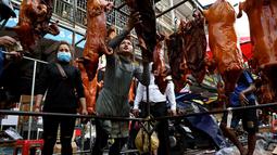 Seorang penjual (tengah) memilih babi panggang untuk pelanggannya di pasar menjelang Tahun Baru Imlek di Phnom Penh, Kamboja, Senin (31/1/2022). Tahun Baru Imlek mengawali Tahun Macan pada 1 Februari. (AFP/Tang Chhin Sothy)