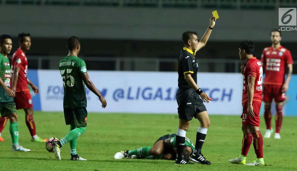 Wasit Ikhsan Prasetya Jati memberi kartu kuning pada pemain Arema FC, Ahmad Bustomi saat melawan PS TNI dilanjutan Liga 1 Indonesia di Stadion Pakansari, Bogor, Senin (3/7). Laga kedua tim berakhir imbang 0-0. (Liputan6.com/Helmi Fithriansyah)