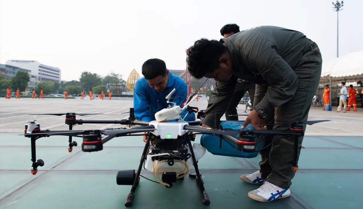 Seorang relawan untuk Bangkok Metropolitan Administration (BMA) mengisi ulang drone penghasil hujan yang menaburkan awan guna menurunkan hujan buatan selama demontrasi di ibu kota Thailand, Kamis (31/1). (Jewel SAMAD/AFP)