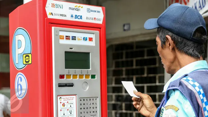 Petugas parkir melakukan transaksi dengan mesin terminal parkir elektronik (TPE) di jalan Sabang, Jakarta, Kamis (25/2). Pemprov DKI Jakarta berencana menambah mesin terminal parkir elektronik (TPE) atau parkir meter. (Liputan6.com/Yoppy Renato)