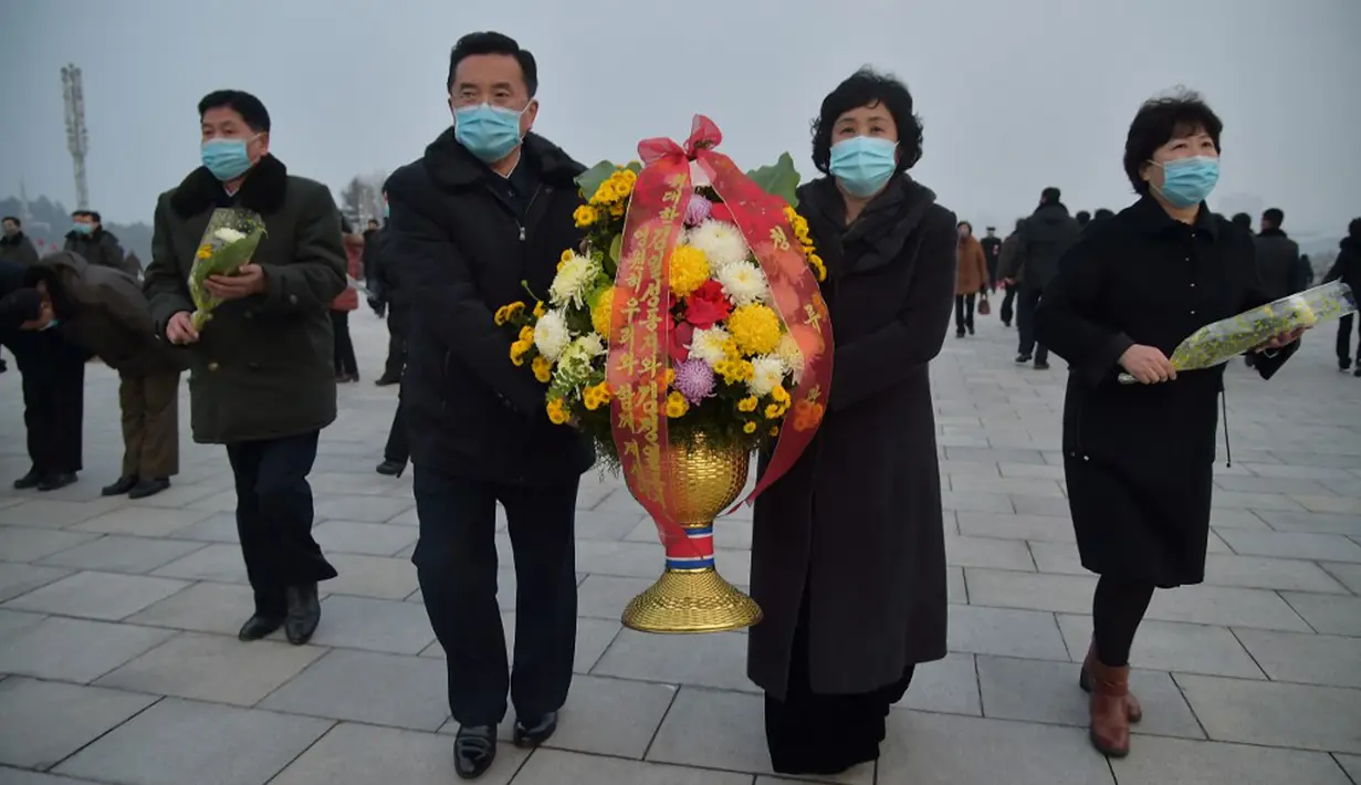 Warga berdatangan untuk memberi penghormatan di depan patung mendiang pemimpin Korea Utara Kim Il-sung dan Kim Jong-il pada peringatan 10 tahun kematian Kim Jong-il, Pyongyang, Korea Utara, 16 Desember 2021. Kim Jong-il adalah ayah dari pemimpin Korea Utara saat ini, Kim Jong-un. (KIM WON JIN/AFP)