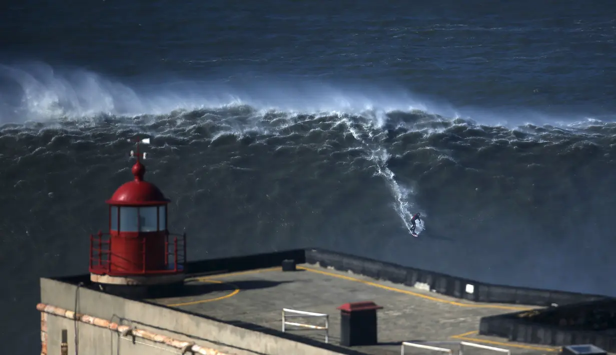 Seorang peselancar bermain diatas ombak yang besar di Praia do Norte, Nazare, Portugal, (19/2/16). Praiado Norte adalah salah satu surga bagi para peselancar dunia. (REUTERS/Rafael Marchante)