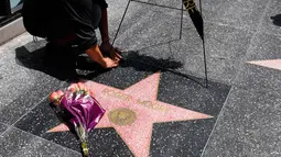Pekerja meletakkan karangan bunga dekat bintang Walk of Fame milik aktor Inggris, Roger Moore, di Hollywood, Los Angeles, Selasa (23/5). Aktor yang namanya dikenal karena memerankan James Bond itu meninggal dunia pada usia 89 tahun. (AP Photo/Jae C. Hong)