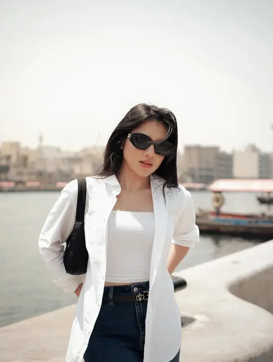 Berpose di depan arsitektur, Davina Karamoy tampil stylish dengan padu padan tank top dan kemeja panjang warna senada. [@davinaakaramoyy].