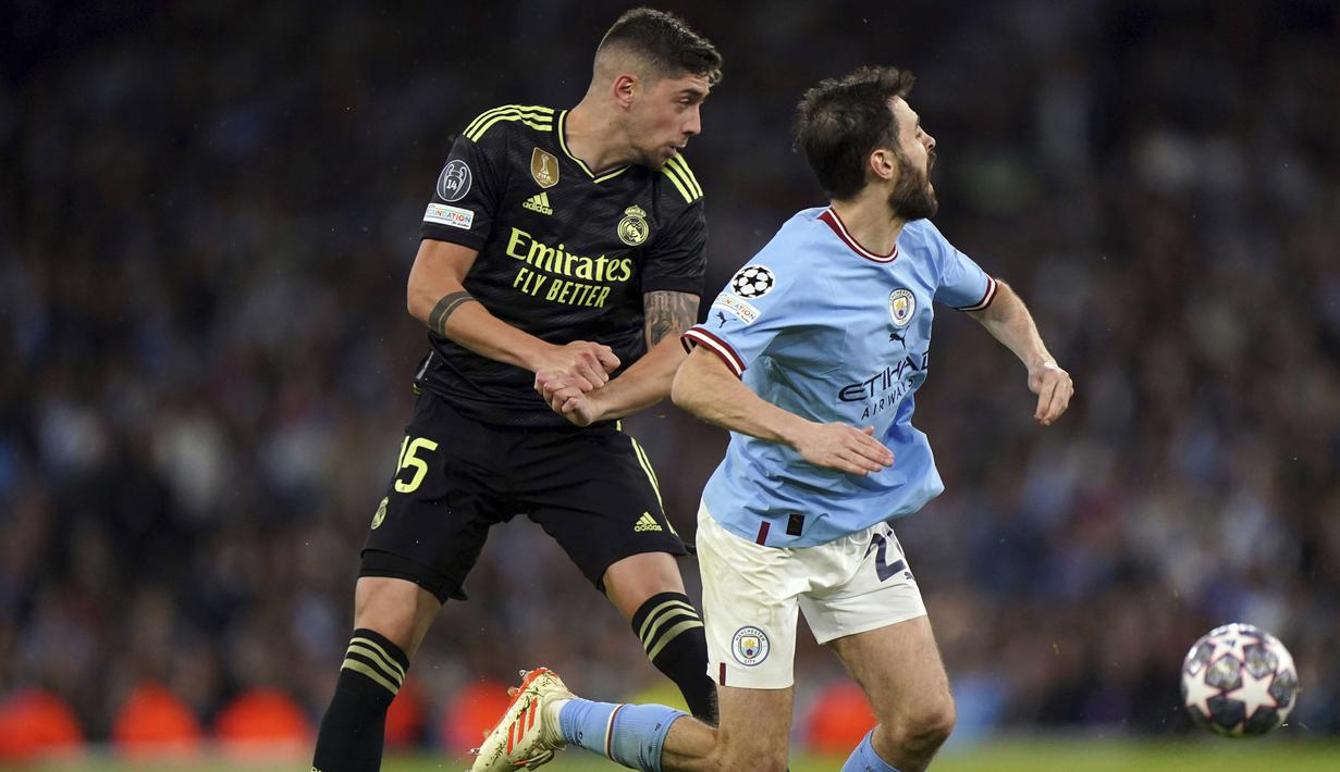 Pemain Manchester City, Bernardo Silva, terjatuh saat berebut bola dengan pemain Real Madrid, Federico Valverde, pada laga semifinal leg kedua di Stadion Etihad, Kamis (18/5/2023). Man City menang dengan skor 4-0. (Tim Goode//PA via AP)