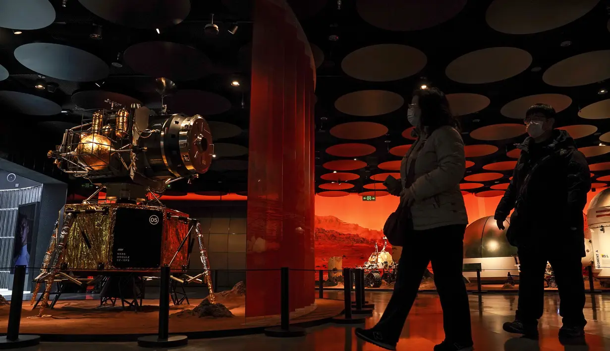 Pengunjung saat mengunjungi pameran yang menampilkan model pesawat ruang angkasa dan penjelajah di Mars di sebuah pusat perbelanjaan di Beijing, (24/2/2021).   Parkir orbit di sekitar Mars untuk mengantisipasi pendaratan penjelajah di planet merah dalam beberapa bulan mendatang. (AP Photo/Andy Wong)
