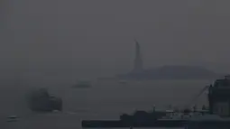 Feri Staten Island berangkat dari terminal Manhattan melalui kabut asap dengan Patung Liberty nyaris tidak terlihat, di New York, Selasa (20/7/2021). Lebih dari 60 kebakaran hutan melanda sekitar 10 negara bagian di AS, menyebabkan langit berkabut hingga New York.  (AP Photo/Julie Jacobson)