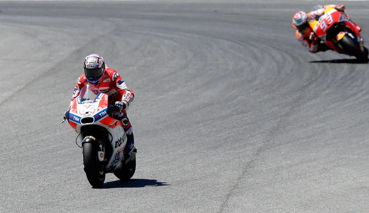 Pembalap Ducati Andrea Dovizioso (kiri), mengungguli pembalap Repsol Honda, Marc Marquez selama MotoGP Catalunya di Barcelona, Minggu (11/6). Memulai lomba dari posisi ketujuh, Dovizioso melesat hingga garis finis. (AP Photo/Manu Fernandez)