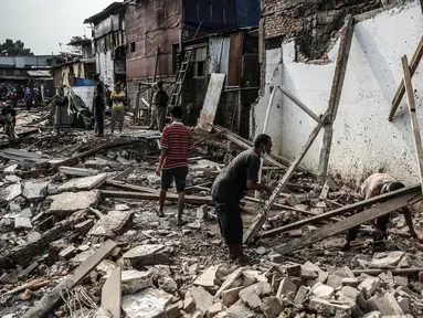 Warga mengumpulkan besi dari puing-puing sisa penertiban bangunan di bantaran Sungai Ciliwung, kawasan Bukit Duri, Jakarta Selatan, Selasa (11/7). Terdapat 355 bangunan yang ditertibkan guna menanggulangi banjir di Jakarta ini (Liputan6.com/Faizal Fanani)