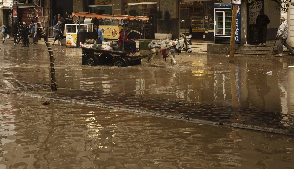 Seorang pedagang mengendarai kereta keledainya di jalan yang banjir saat hujan lebat di Kota Gaza, Selasa (8/11/2022). Hujan deras menyebabkan banjir bandang di Jalur Gaza pada hari Selasa, di mana infrastruktur yang bobrok sering membuat air banjir tidak surut, memperpanjang kerusakan. (AP Photo/Adel Hana)