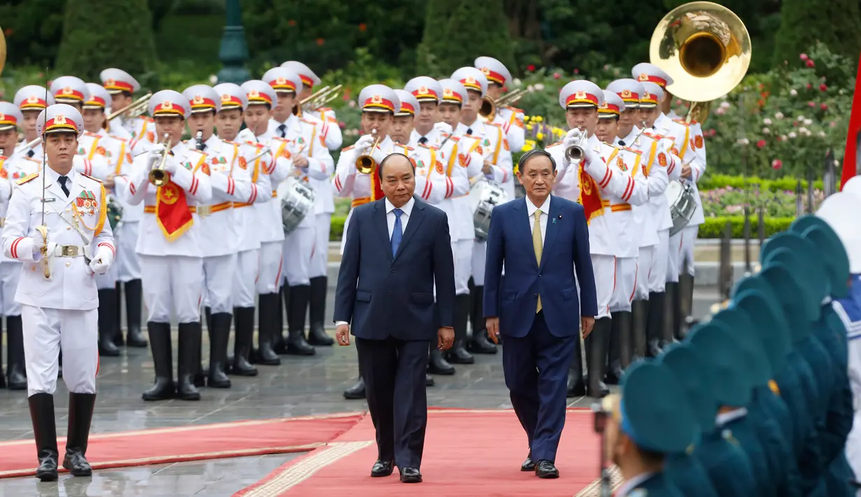 PM Jepang, Yoshihide Suga (kanan) bersama PM Vietnam, Nguyen Xuan Phuc saat upacara penyambutan tamu negara di Istana Kepresidenan, di Hanoi, Vietnam, Senin (19/10/2020). Yoshihide Suga melakukan kunjungan resmi ke Vietnam hingga 20 Oktober 2020. (Kham/Pool Photo via AP)