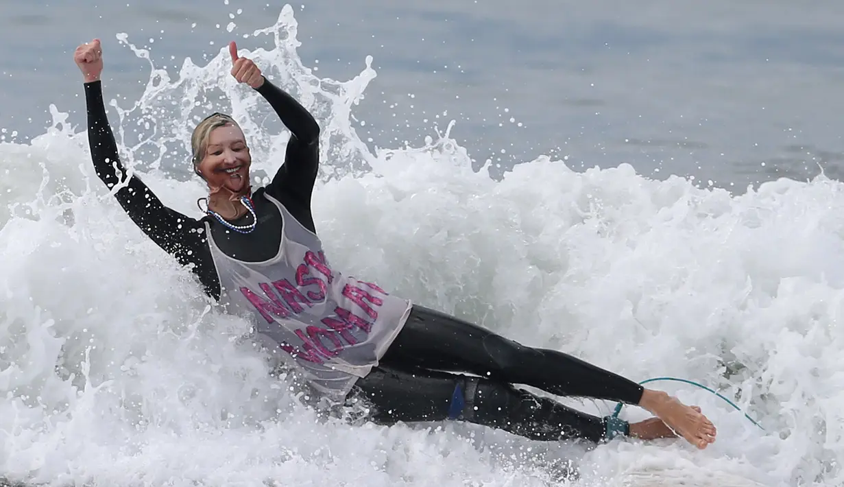 Peserta memakai topeng capres AS, Hillary Clinton saat mengikuti kontes surfing Haunted Heats Halloween di Santa Monica, AS (29/10). Acara ini untuk merayakan hari Halloween yang jatuh pada tanggal 31 Oktober. (REUTERS/Lucy Nicholson)