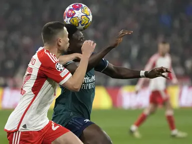 Bek Bayern Munchen Raphael Guerreiro berebut bola dengan penyerang Arsenal Bukayo Saka pada duel leg kedua perempat final Liga Champions 2023/2024 di Allianz Arena pada Kamis (18/4/2024) dinihari WIB. (AP Photo/Matthias Schrader)