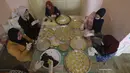 Sejumlah perempuan mengenakan sarung tangan dan masker saat membuat biskuit tradisional jelang Hari Raya Idul Fitri di Kota Tua Hebron, Tepi Barat, Palestina, Selasa (19/5/2020). Biskuit tradisional akan dijual secara online karena pandemi virus corona COVID-19. (HAZEM BADER/AFP)