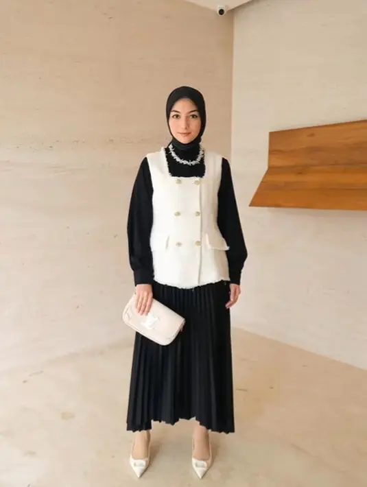 Citra Kirana terlihat feminin dengan outfit monokrom. Ia padukan kemeja long sleeve dengan pleated skirt hitam dan double breated tweed vest yang trendy [@citra_ciki]