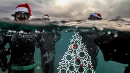 Penyelam berpose saat akan menempatkan pohon Natal di dasar laut lepas pantai Tripoli, Lebanon, Selasa (18/12). Hal ini dilakukan untuk menyambut Natal. (IBRAHIM CHALHOUB/AFP)