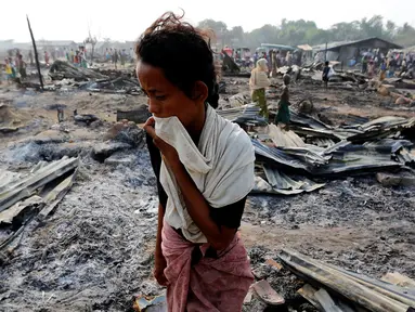 Seorang wanita berjalan di antara puing-puing setelah kebakaran sebuah kamp bagi pengungsi Muslim Rohingya di negara bagian Rakhine, Myanmar, Selasa (3/5). Kebakaran menghancurkan 50 hunian sementara dalam kamp bagi pengungsi asing. (REUTERS/Soe Zeya Tun)
