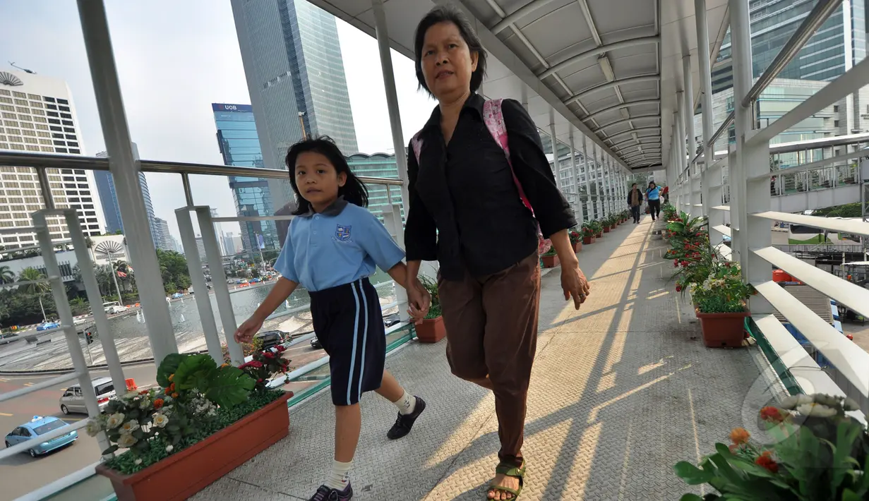 Warga berjalan menggunakan jembatan penyebrangan orang (JPO)  Bundaran HI, Jakarta, Jumat (20/3/2015). Pemprov DKI akan menjadikan JPO di kawasan Bundaran HI sebagai standar JPO yang ada di Jakarta nanti. (Liputan6.com/Faizal Fanani)