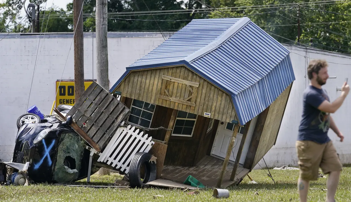 Sebuah mobil dan gedung utilitas bersandar satu sama lain di Waverly, Tennessee, Minggu (22/8/2021). Banjir parah yang melanda Middle Tennessee, AS, menyebabkan sedikitnya 22 orang tewas, sementara sekitar 50 orang lainnya dilaporkan masih hilang. (AP Photo/Mark Humphrey)