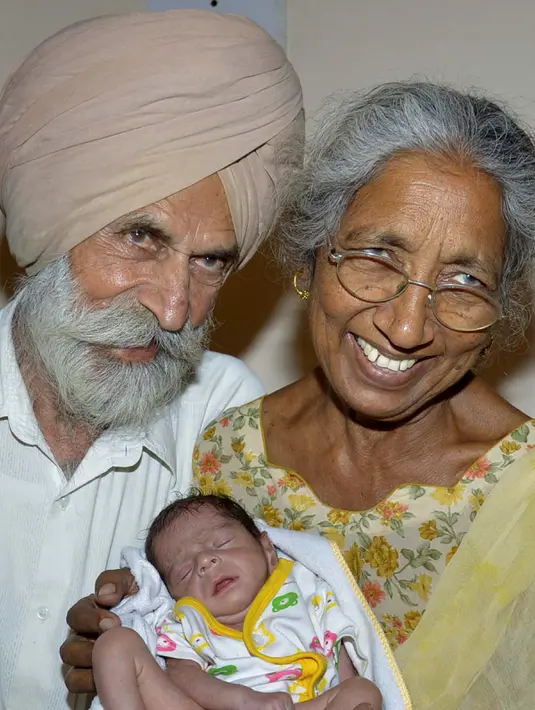 Pasangan Daljinder Kaur (kiri) bersama sang suami Mohinder Singh Gill saat menggendong bayi kesayangan mereka di Amritsar, India, (11/5). Bayi laki-laki dengan bobot dua kilogram tersebut lahir dari seorang wanita berumur 70 tahun. ( NARINDER NANU / AFP)
