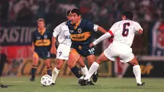 Pemain sepak bola Boca Juniors Diego Maradona (tengah) mencoba menghindari pemain Universidad de Chile Ronald Fuentes pada pertandingan persahabatan di Santiago, Chile, 12 Desember 1995. Legenda sepak bola Argentina Diego Maradona meninggal dunia pada 25 November 2020. (MARTIN THOMAS/AFP)
